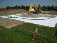 Scavo platea, posa di geotessuto e di drenaggio con ghiaone lavato, con posa di tubo drenante.
